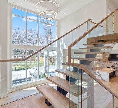 A modern floating staircase with a glass railing.