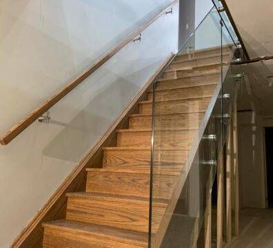 A straight wooden staircase with a glass railing.
