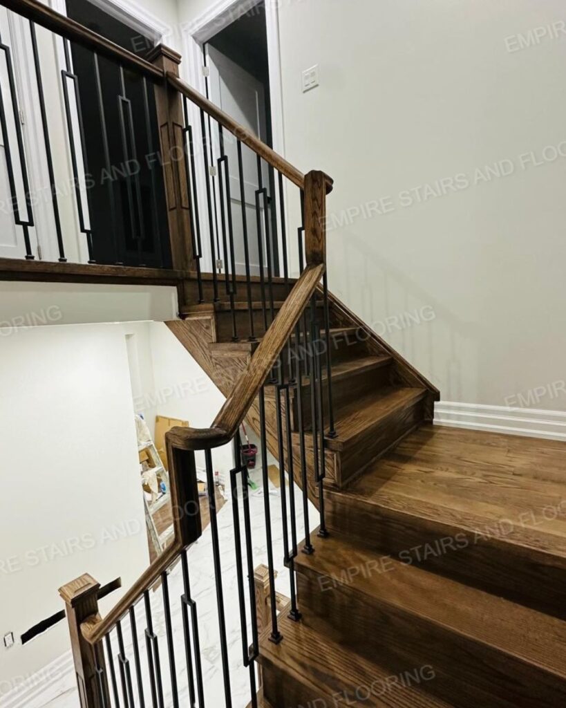 A renovated staircase with dark wood and iron railing.